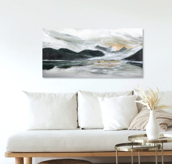 PNW Landscape art painting with dark green rolling mountains and a warm sunset intbetween with grey stormy clouds brewing above, hung on a beige wall above a cream coloured couch with wood frame