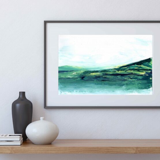 In a black frame, Serene Landscape Painting with brlue and green marbled mountains against a white sky and white water, hung on a white wall above a natural wood shelf with a black vase, a white vase and a small stack of books